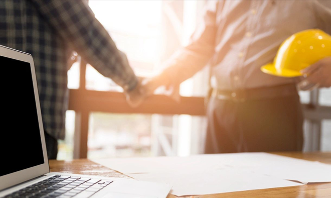 Two people holding hands over a table with papers.