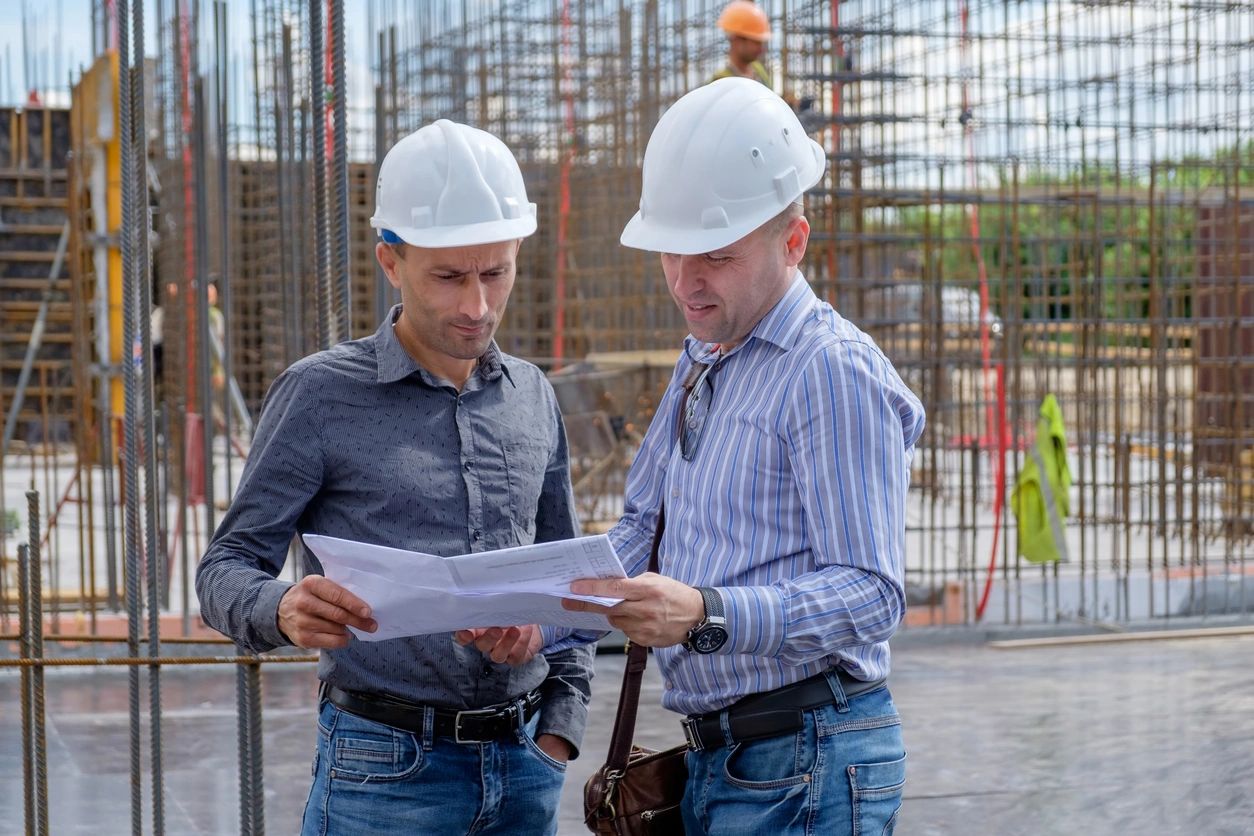 Two construction workers review blueprints.